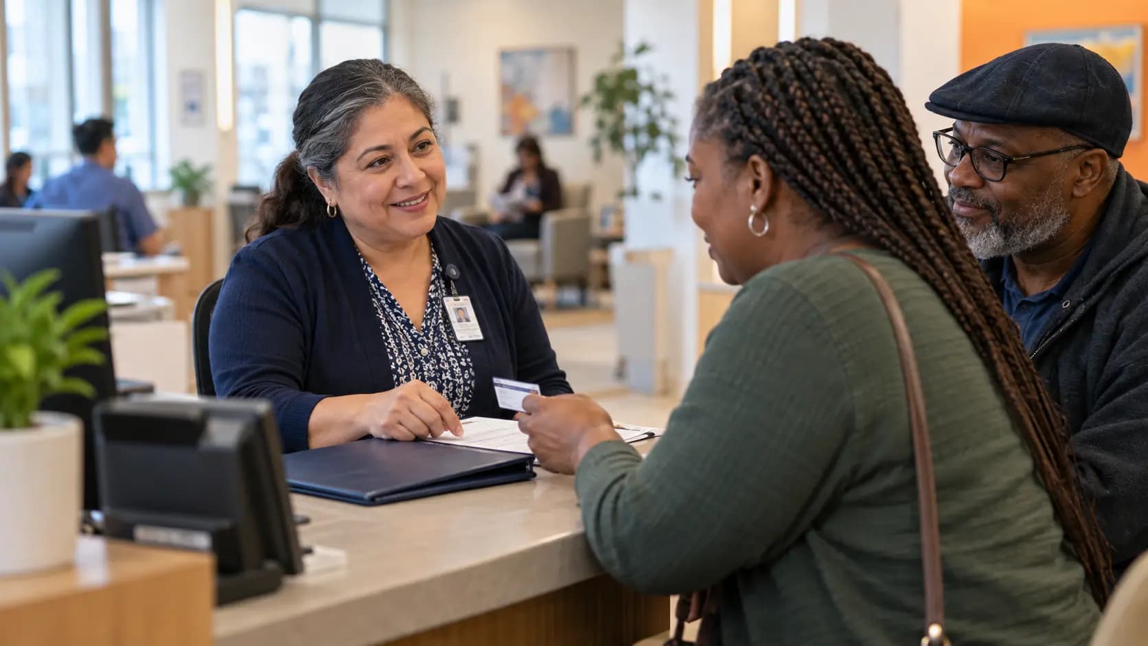 Patient-access coordinator helping a patient at a clinic desk