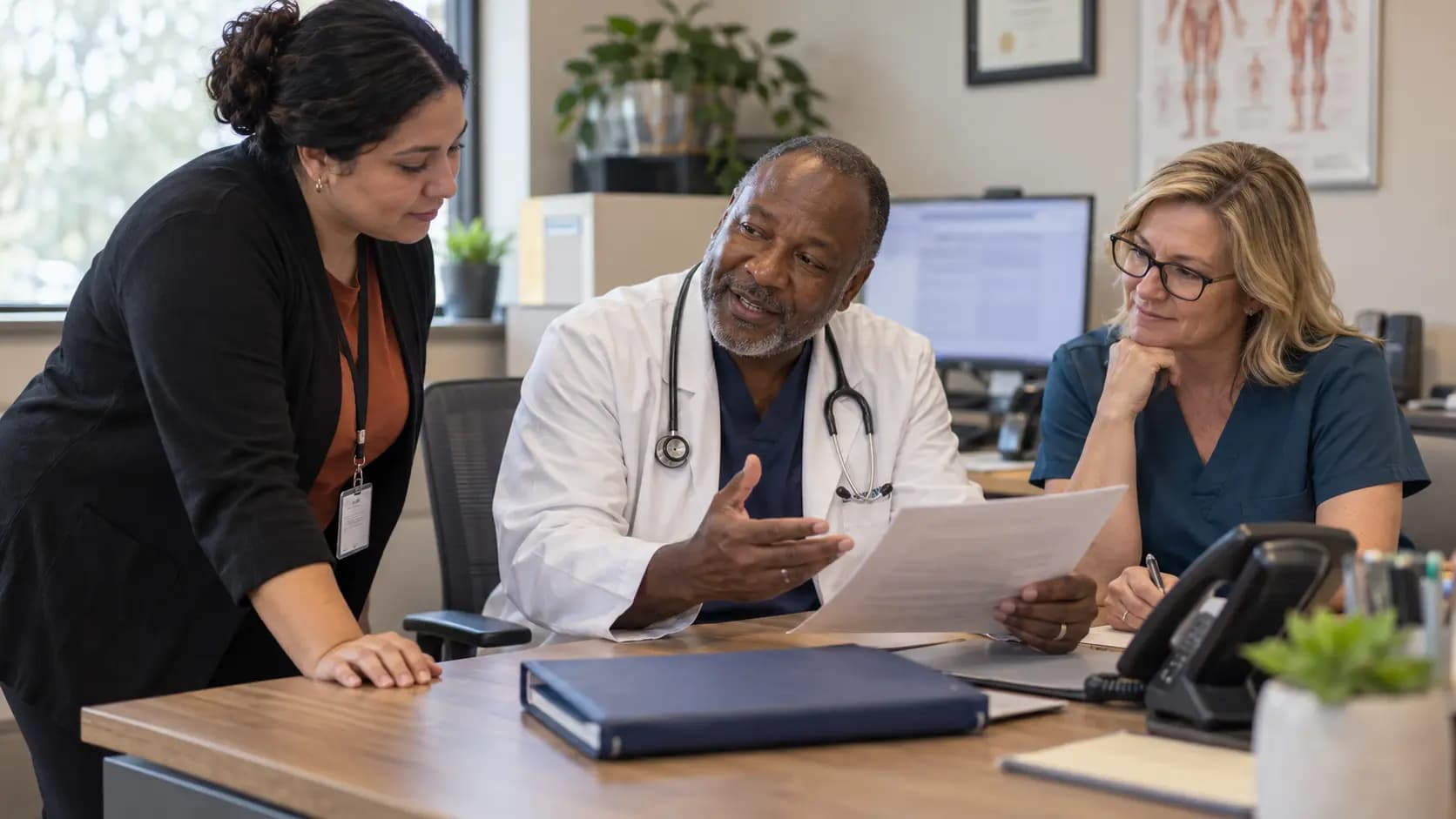 Practice manager and clinician reviewing payer requirements with a specialist