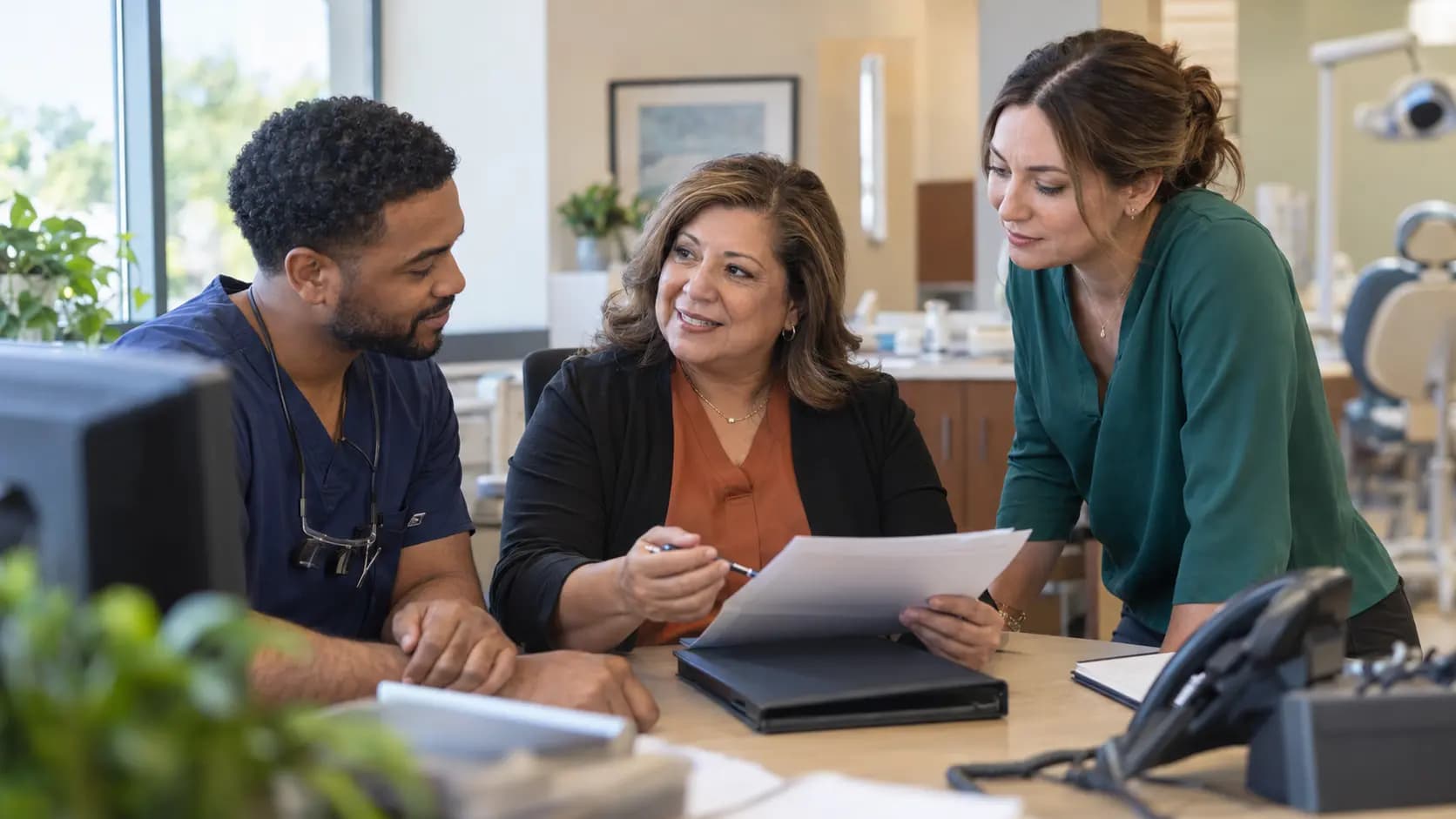 Practice manager and clinician reviewing payer requirements with a specialist