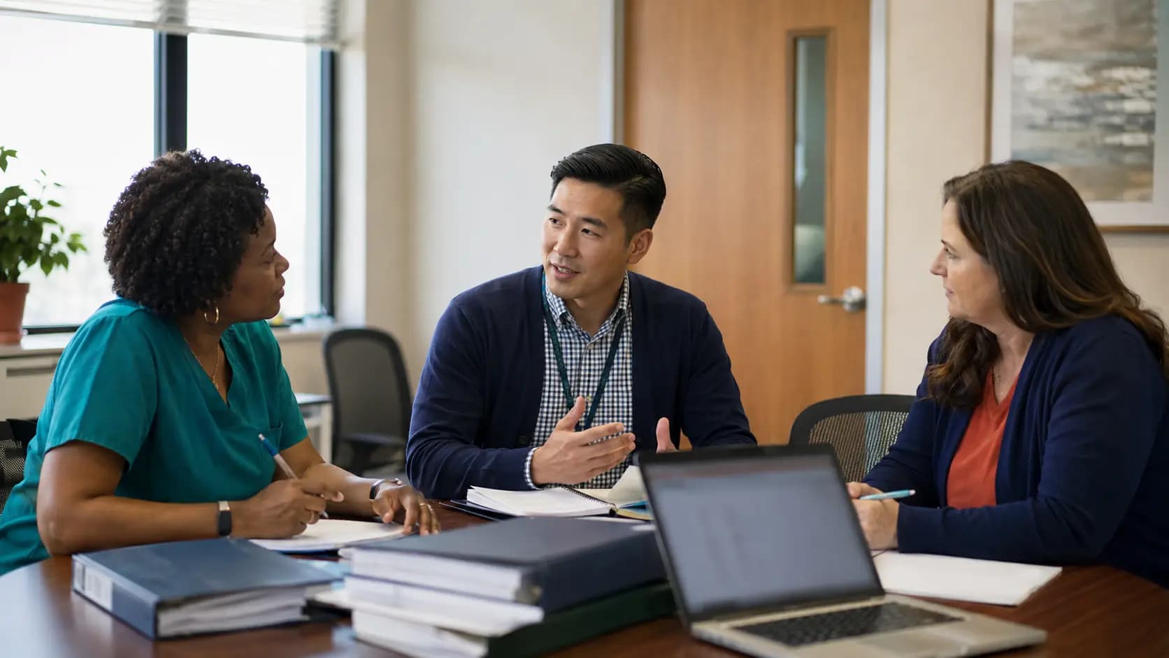 Healthcare compliance officer meeting with a clinician and practice manager