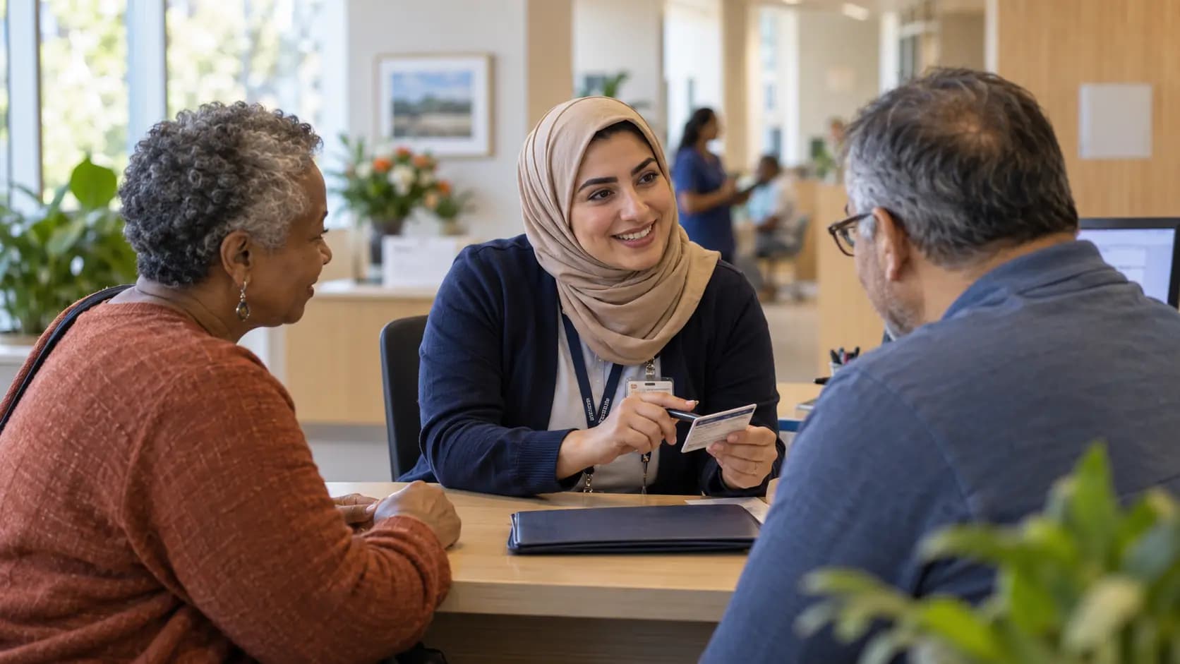 Patient-access coordinator helping a patient at a clinic desk Patient-access coordinator helping a patient at a clinic desk