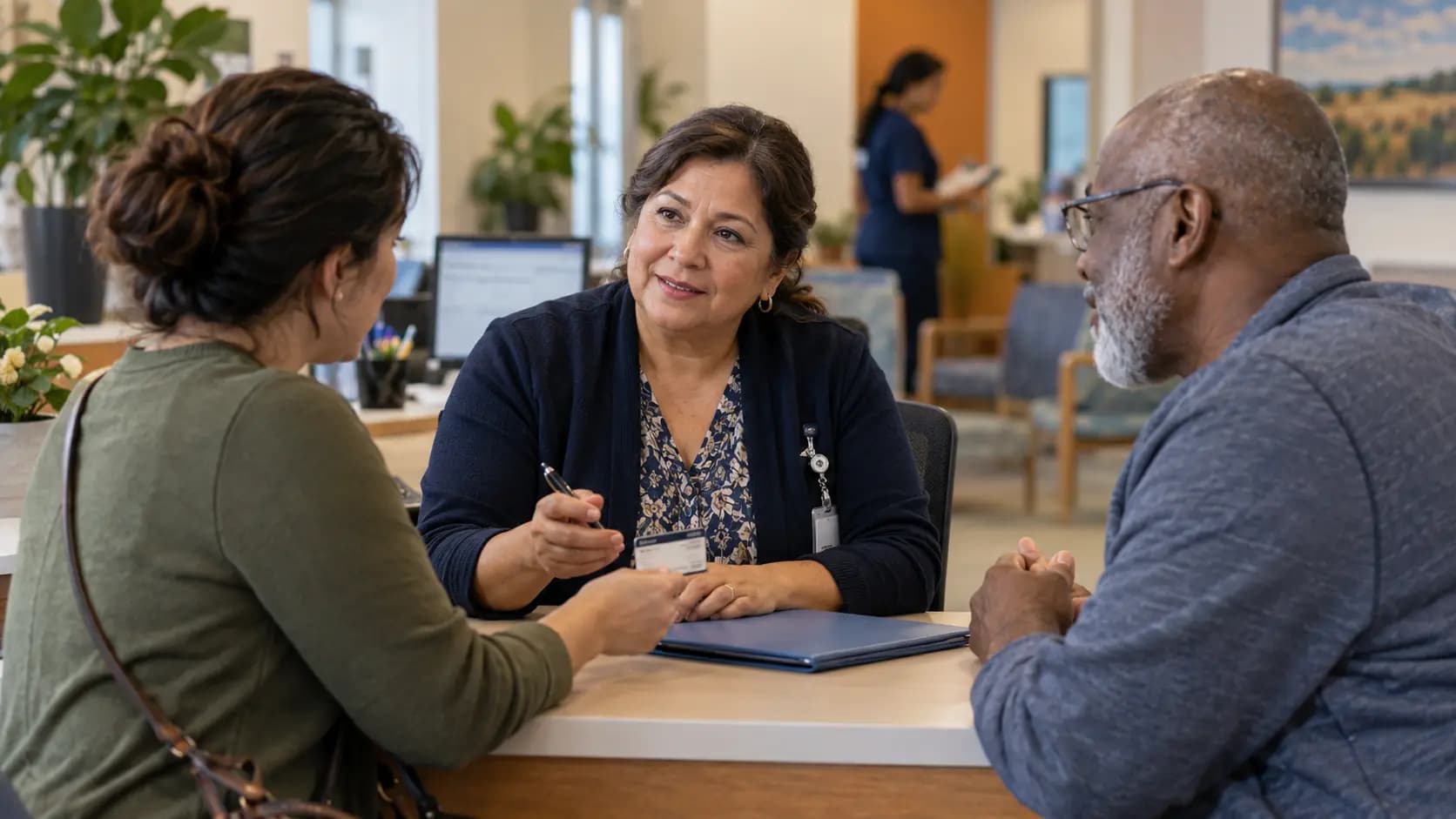Patient-access coordinator helping a patient at a clinic desk Patient-access coordinator helping a patient at a clinic desk