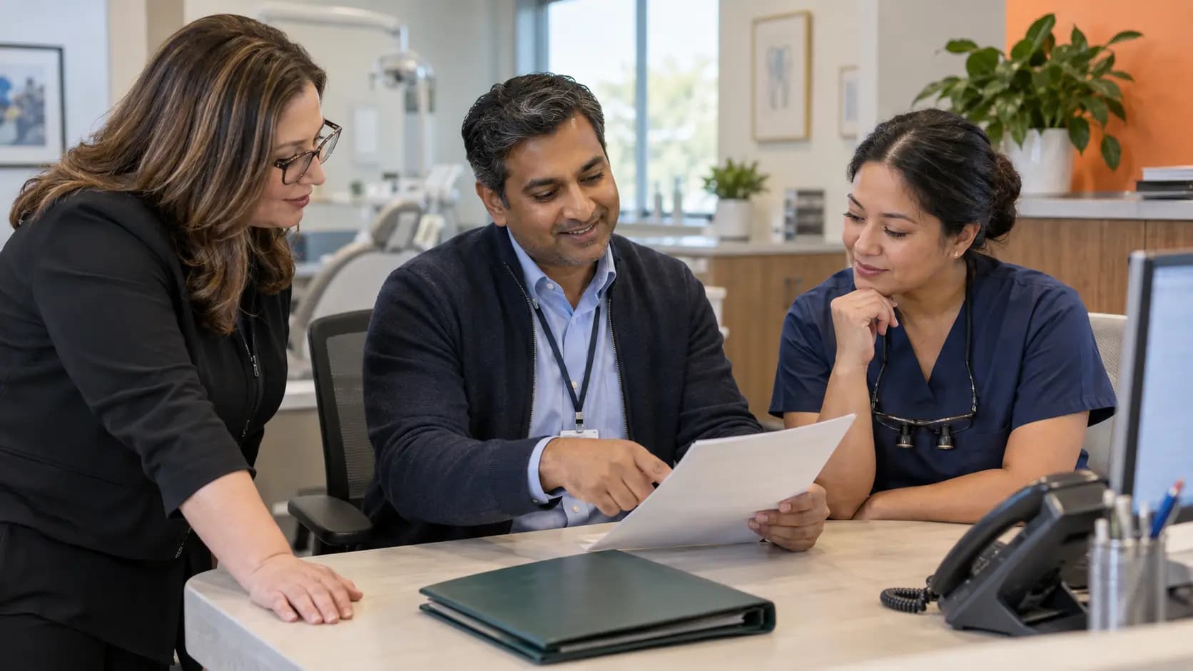 Practice manager and clinician reviewing payer requirements with a specialist