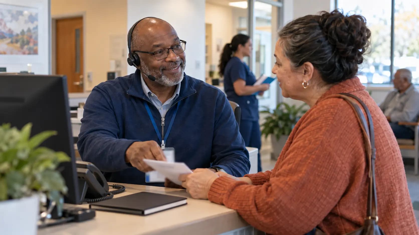 Reception colleague wearing a headset and handing a document to a visitor