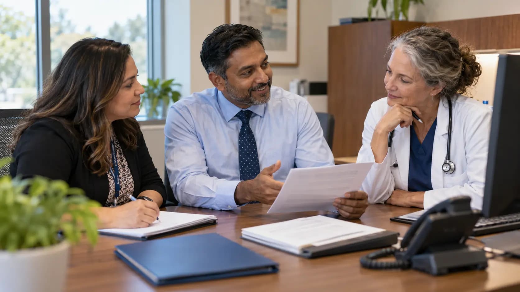 Practice manager and clinician reviewing payer requirements with a specialist