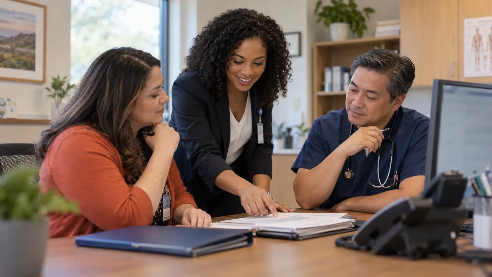 Practice manager and clinician reviewing payer requirements with a specialist