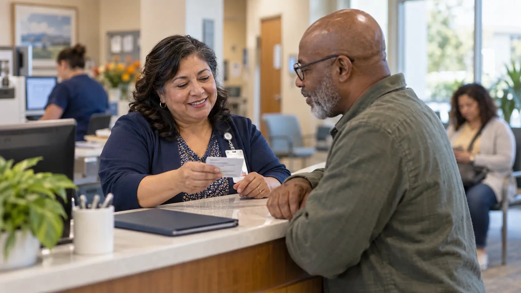 Patient-access coordinator helping a patient at a clinic desk