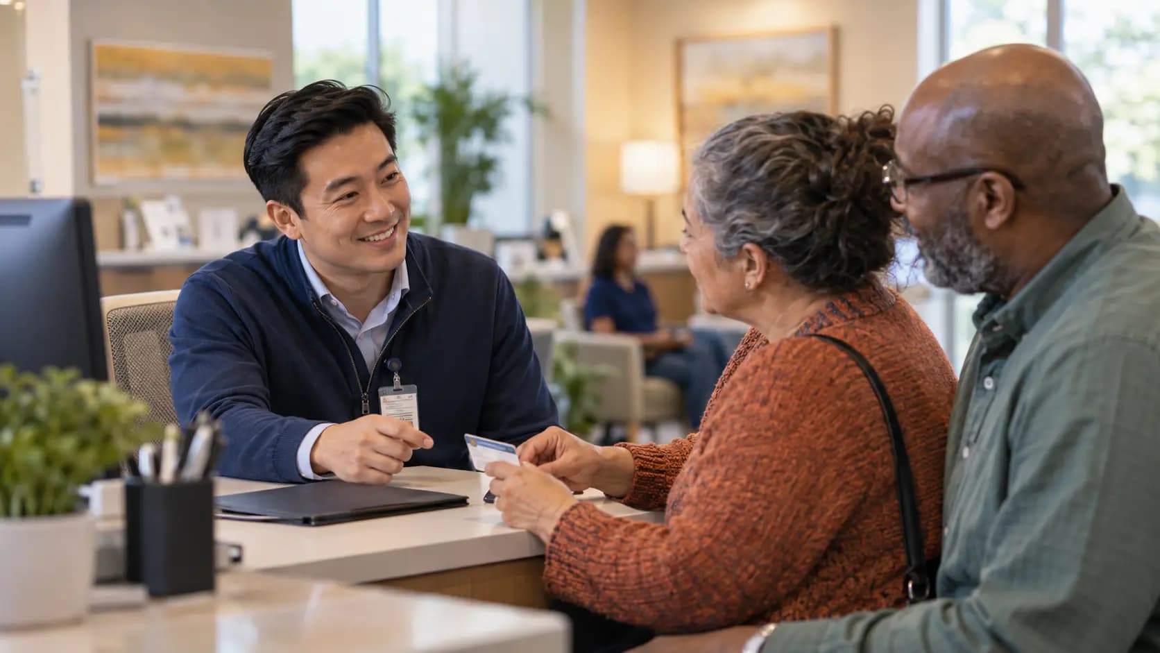 Patient-access coordinator helping a patient at a clinic desk Patient-access coordinator helping a patient at a clinic desk
