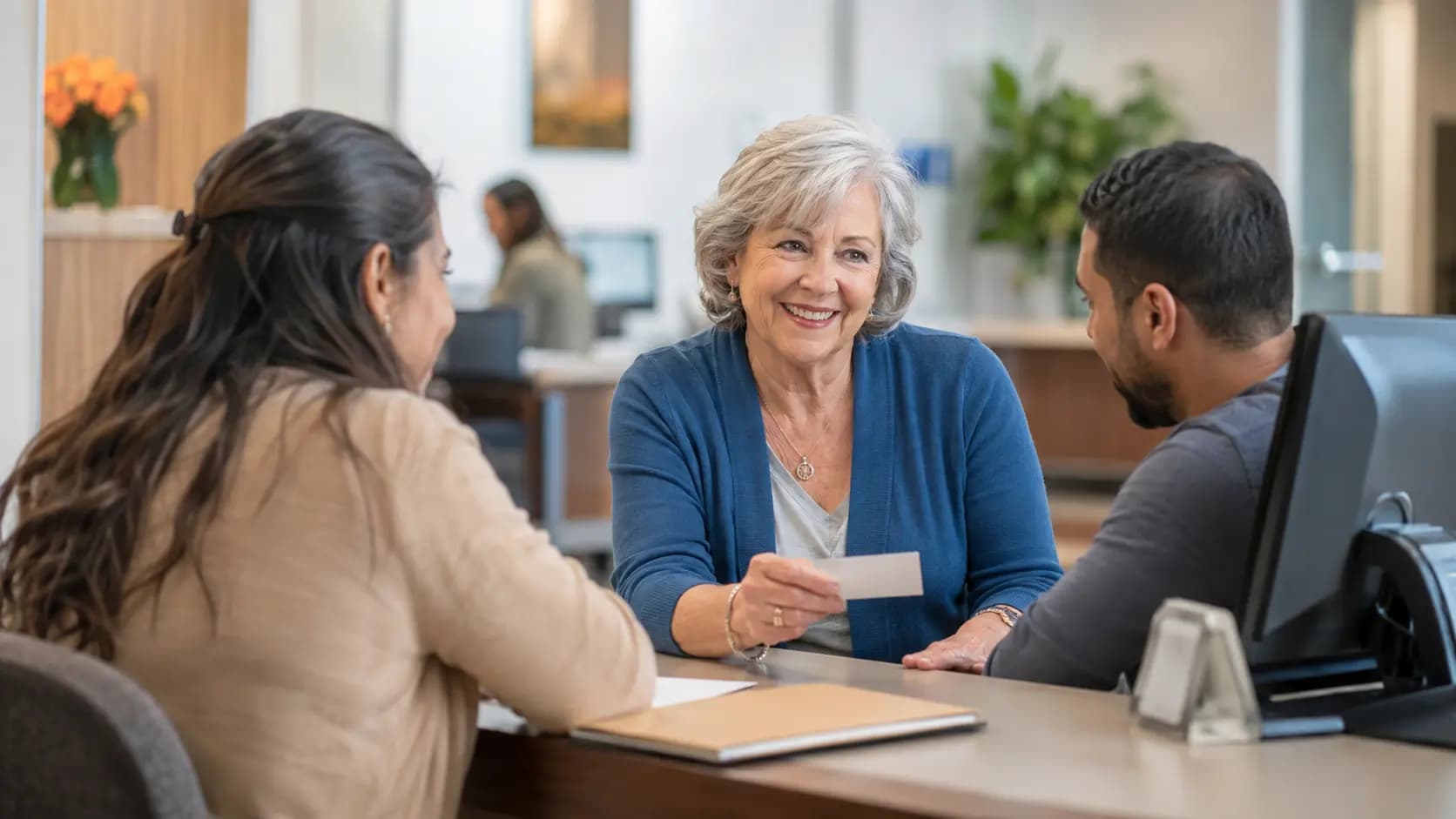 Patient-access coordinator helping a patient at a clinic desk Patient-access coordinator helping a patient at a clinic desk