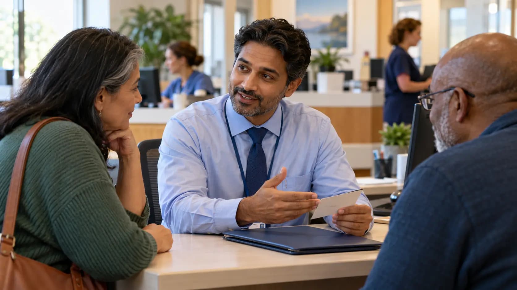 Patient-access coordinator helping a patient at a clinic desk Patient-access coordinator helping a patient at a clinic desk