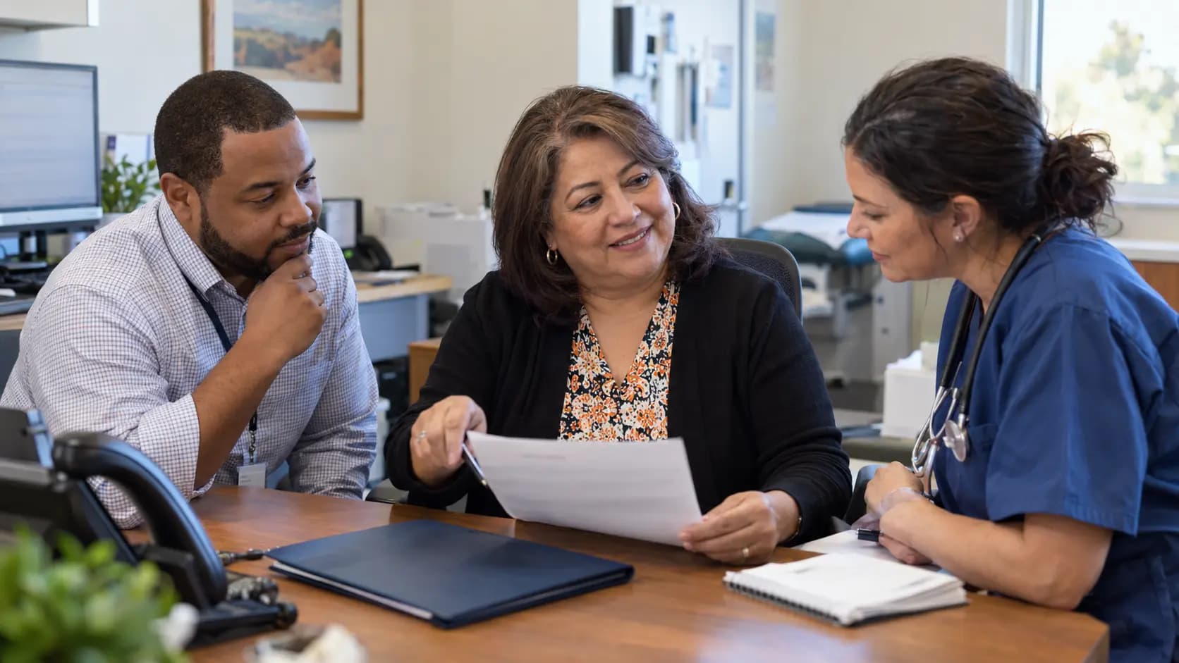 Practice manager and clinician reviewing payer requirements with a specialist