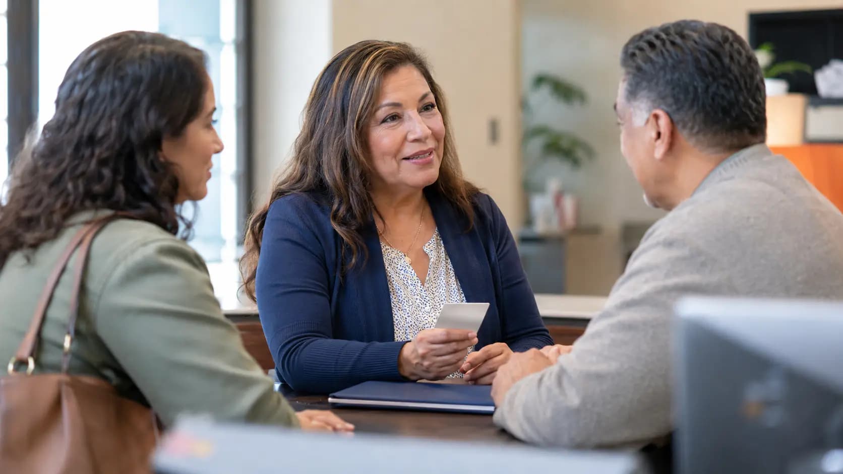 Patient-access coordinator helping a patient at a clinic desk