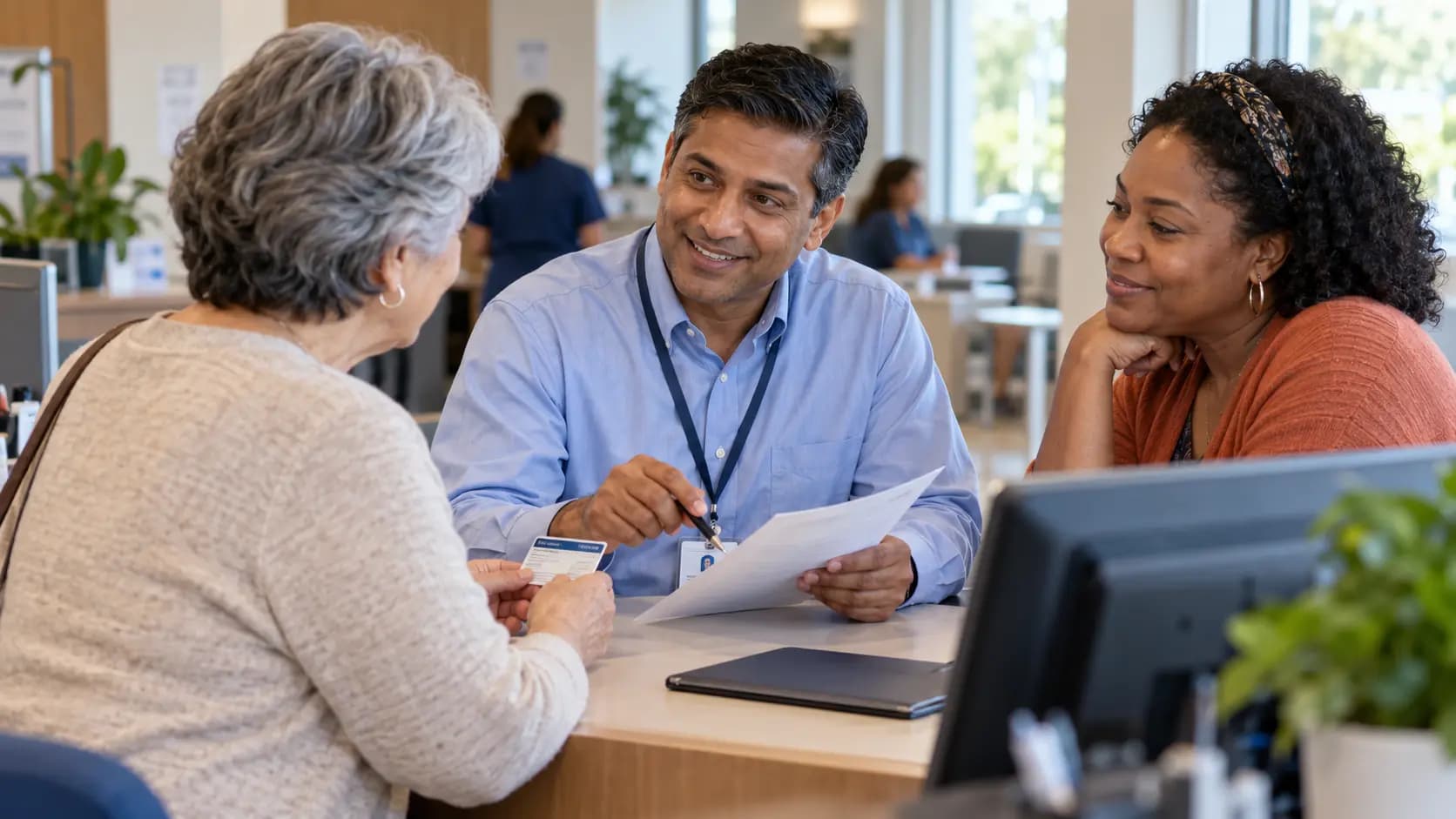 Patient-access coordinator helping a patient at a clinic desk Patient-access coordinator helping a patient at a clinic desk