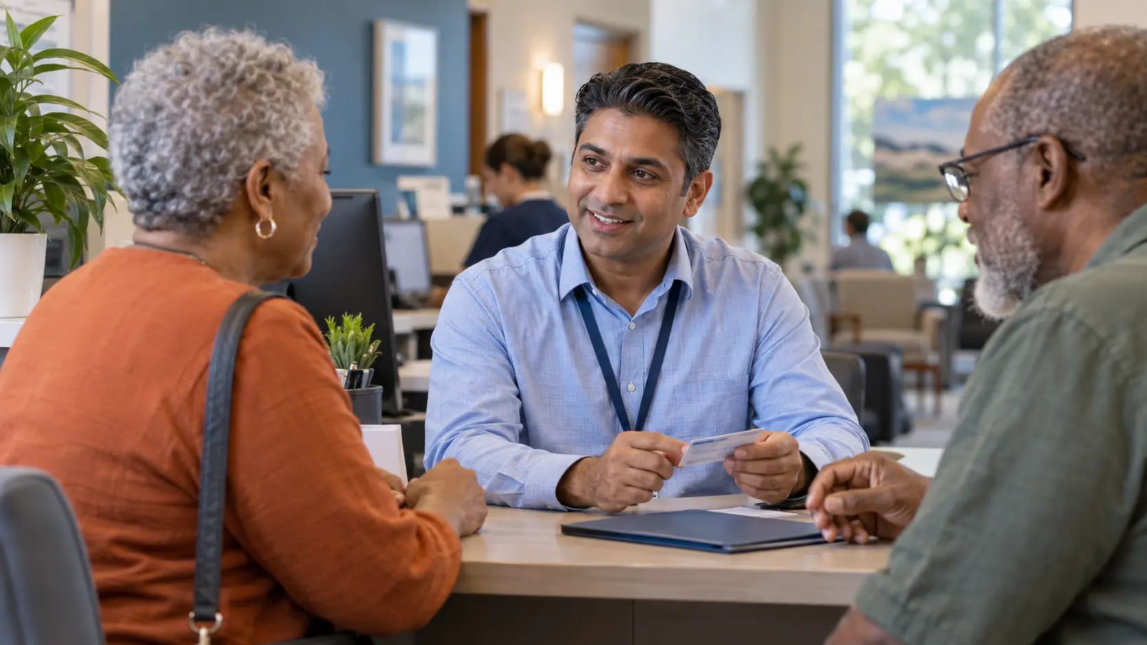 Patient-access coordinator helping a patient at a clinic desk Patient-access coordinator helping a patient at a clinic desk