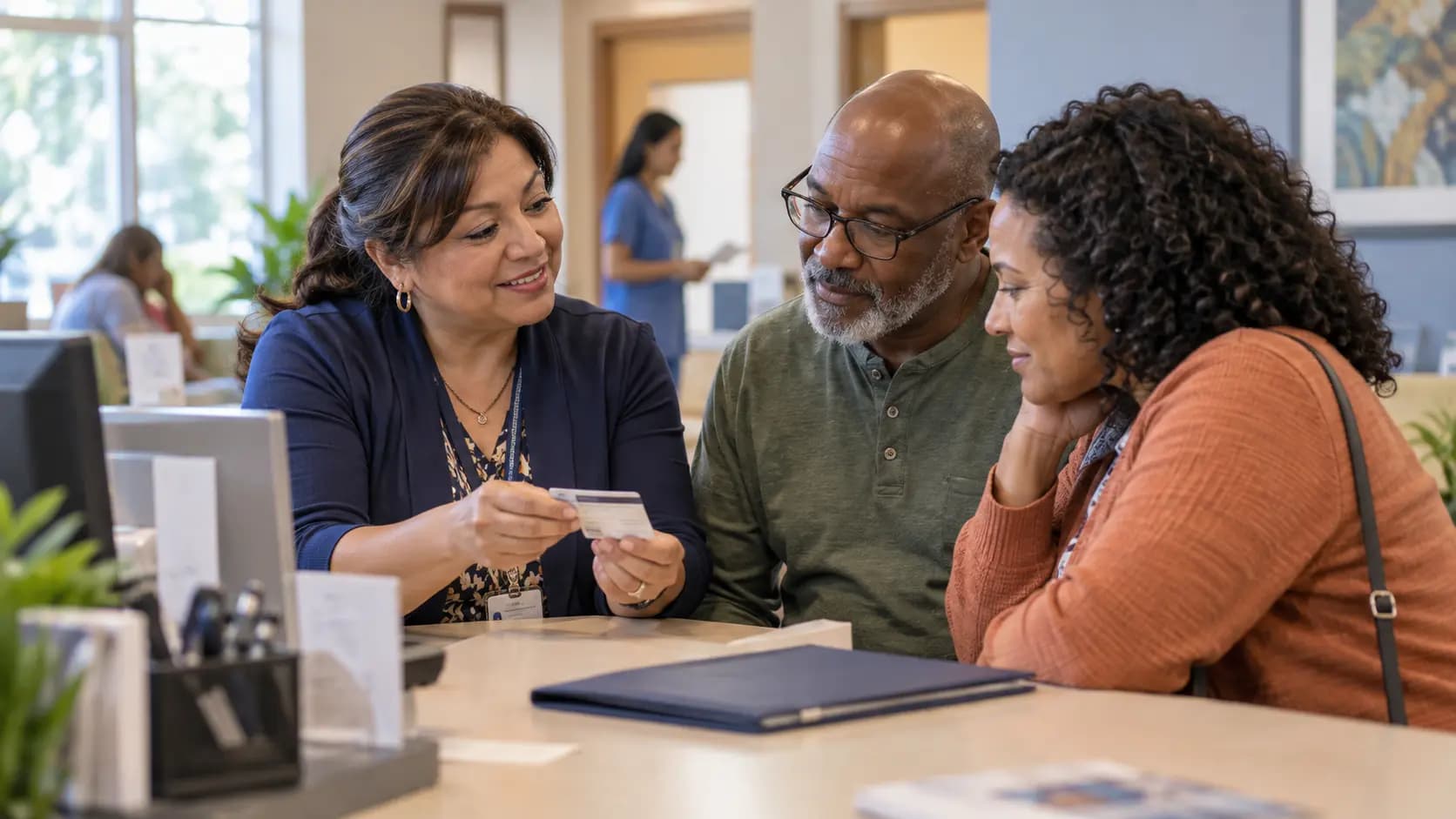 Patient-access coordinator helping a patient at a clinic desk Patient-access coordinator helping a patient at a clinic desk