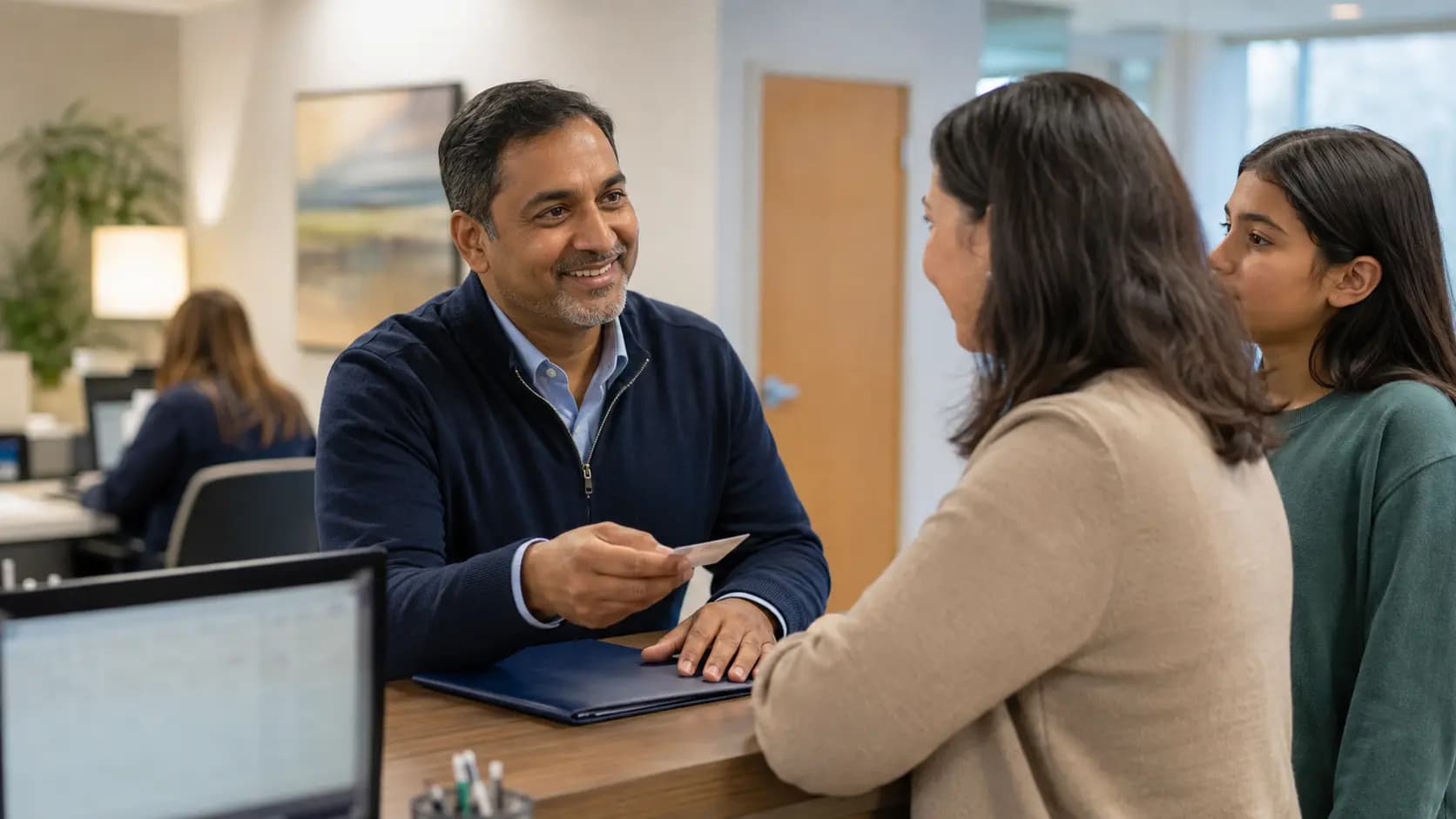 Patient-access coordinator helping a patient at a clinic desk
