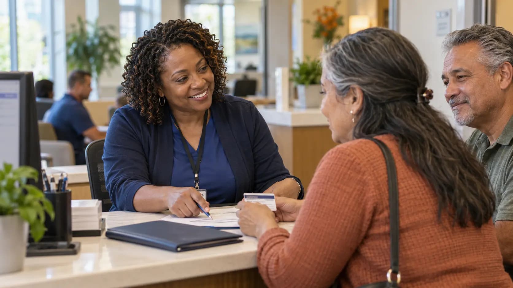 Patient-access coordinator helping a patient at a clinic desk Patient-access coordinator helping a patient at a clinic desk