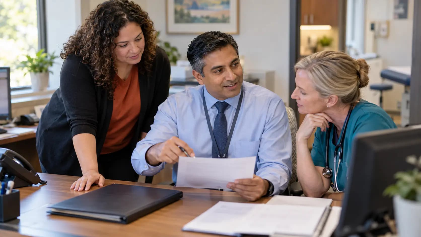Practice manager and clinician reviewing payer requirements with a specialist