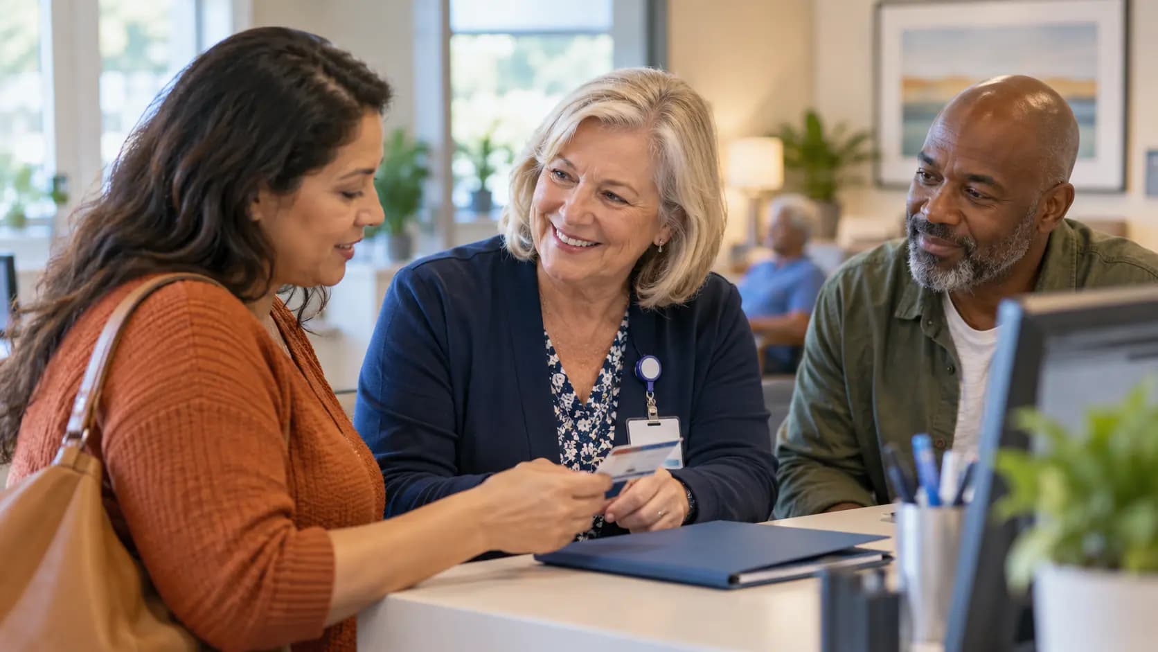 Patient-access coordinator helping a patient at a clinic desk Patient-access coordinator helping a patient at a clinic desk
