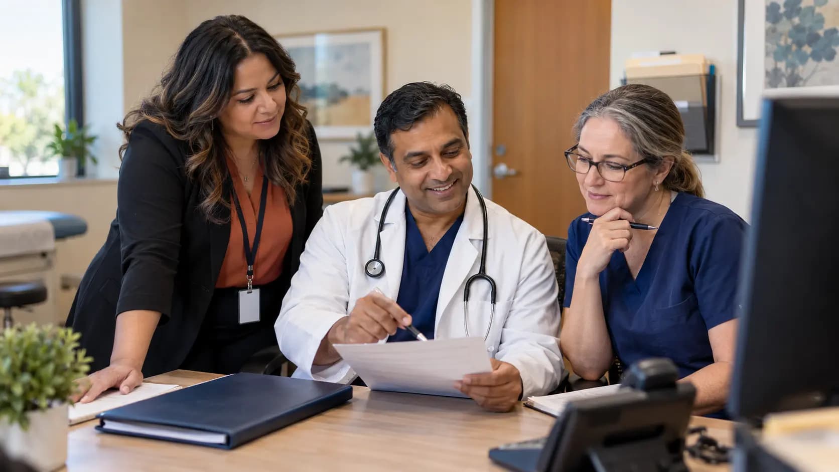 Practice manager and clinician reviewing payer requirements with a specialist