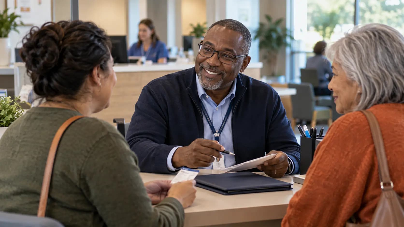 Patient-access coordinator helping a patient at a clinic desk Patient-access coordinator helping a patient at a clinic desk