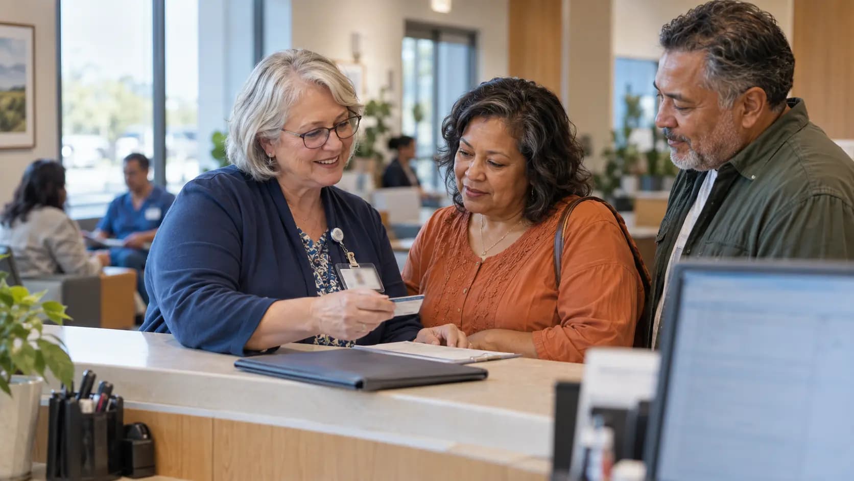 Patient-access coordinator helping a patient at a clinic desk
