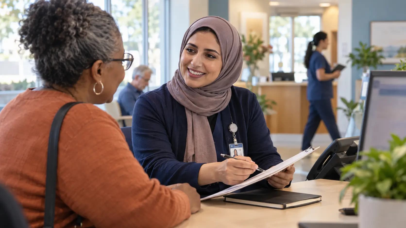 Reception colleague reviewing a clipboard with a visitor at a clinic desk