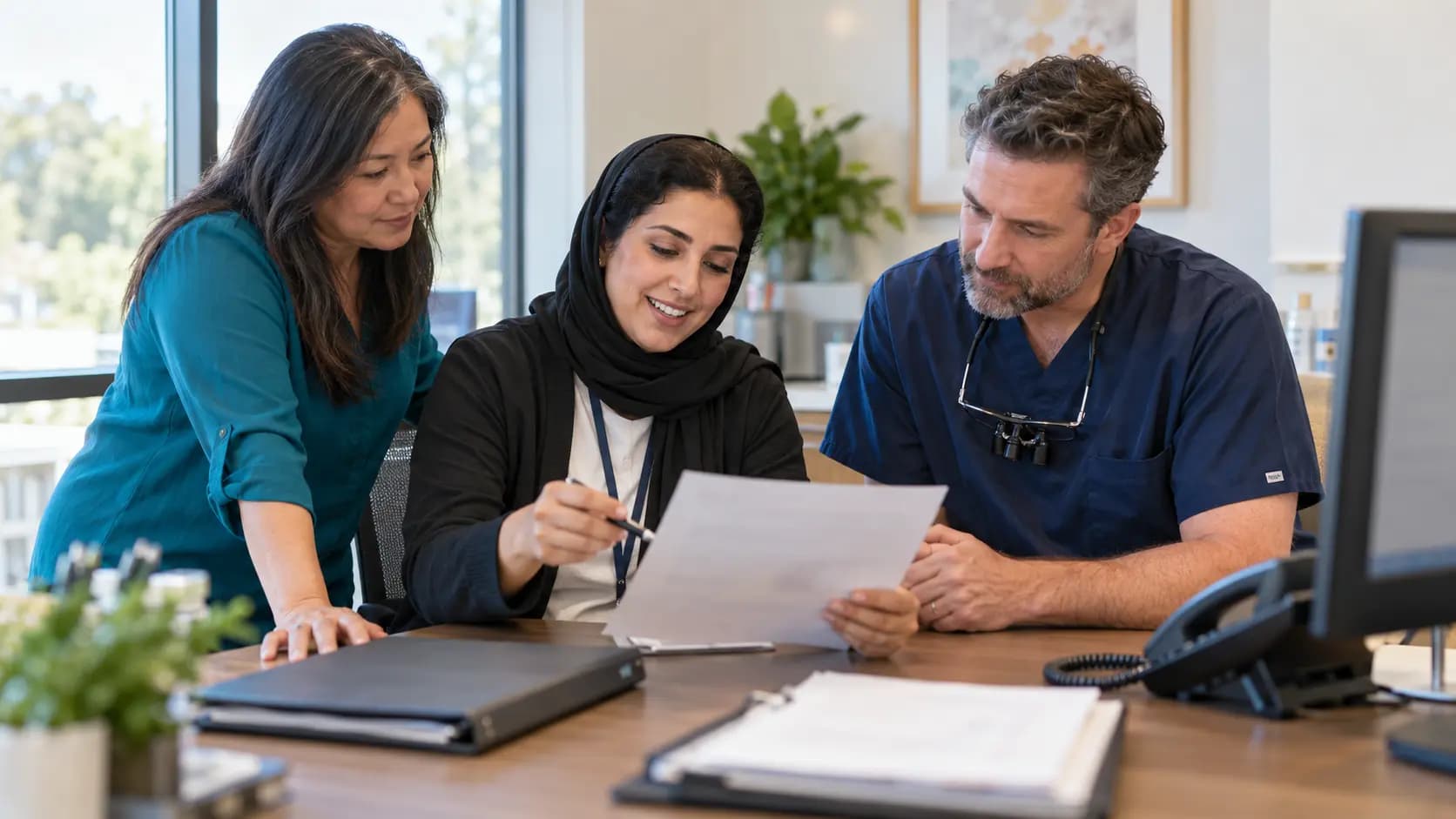 Practice manager and clinician reviewing payer requirements with a specialist