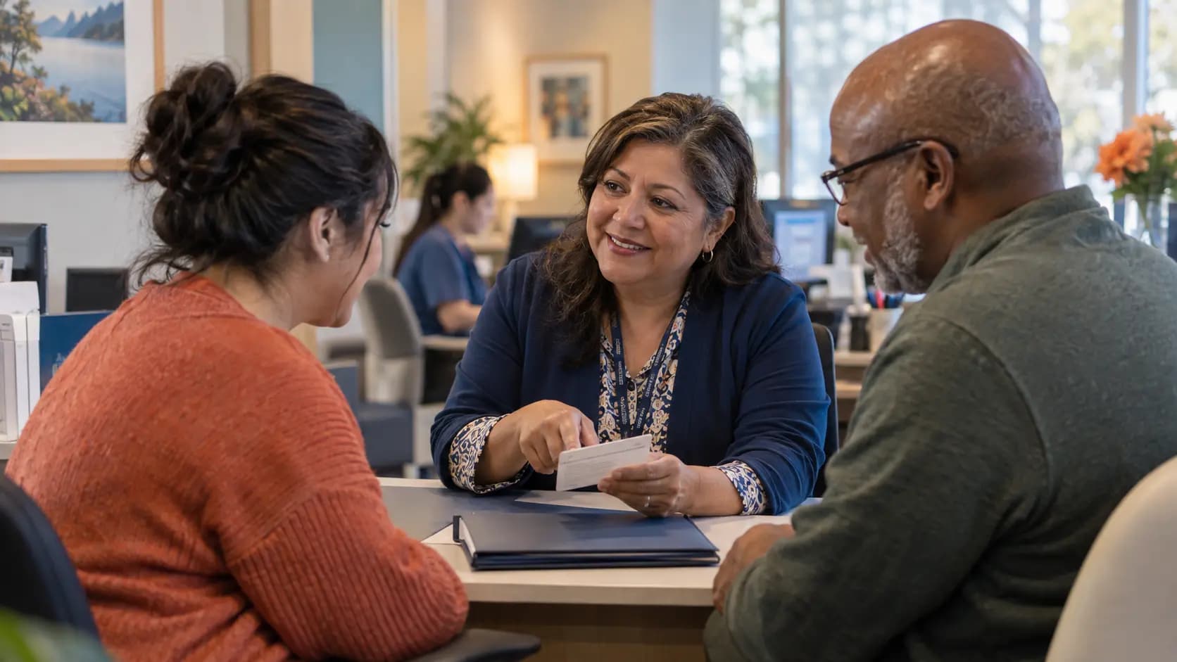 Patient-access coordinator helping a patient at a clinic desk Patient-access coordinator helping a patient at a clinic desk