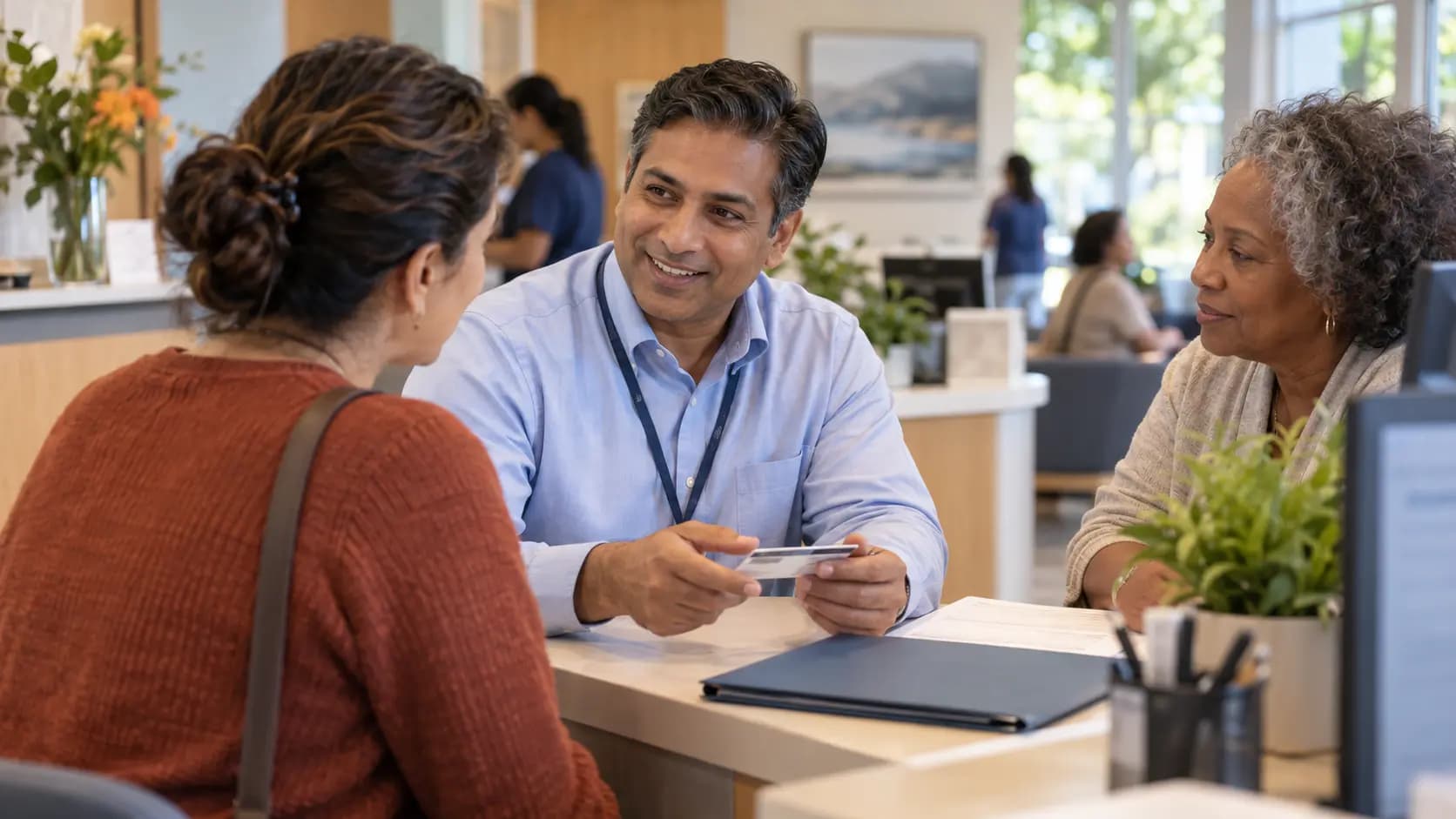 Patient-access coordinator helping a patient at a clinic desk